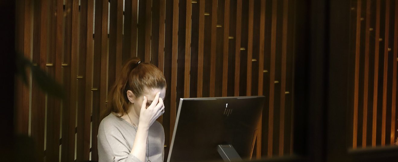 femme travaillant sur ordinateur portable, visage dans les mains, expression de doute et réflexion