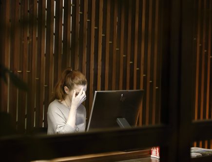 femme travaillant sur ordinateur portable, visage dans les mains, expression de doute et réflexion