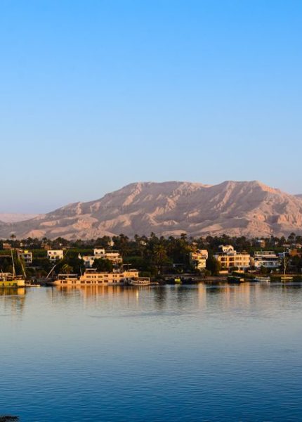 Captivating view of the Nile River with lush greenery and distant desert mountains in Egypt.