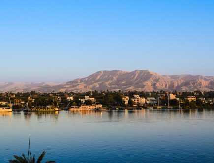 Captivating view of the Nile River with lush greenery and distant desert mountains in Egypt.
