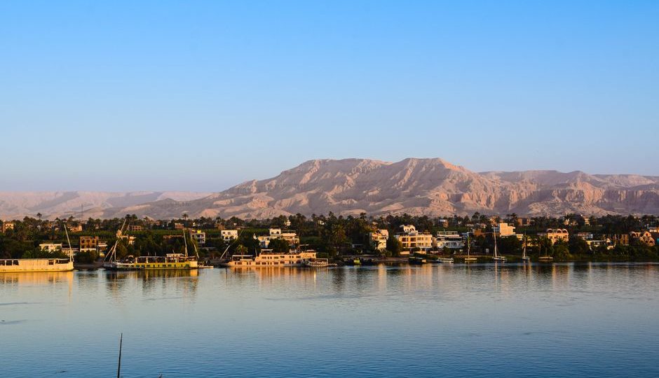 Captivating view of the Nile River with lush greenery and distant desert mountains in Egypt.