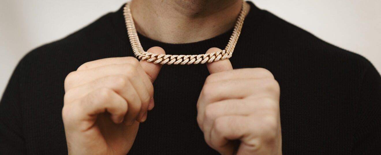 homme portant une chaîne en or et un bracelet assorti sur fond blanc
