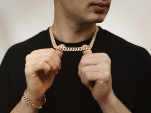 homme portant une chaîne en or et un bracelet assorti sur fond blanc